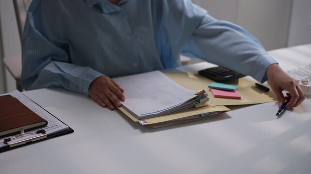 Office worker reviewing organized financial paperwork marked with colorful index tabs, representing accounting document verification, bookkeeping preparation, and efficient business administration.