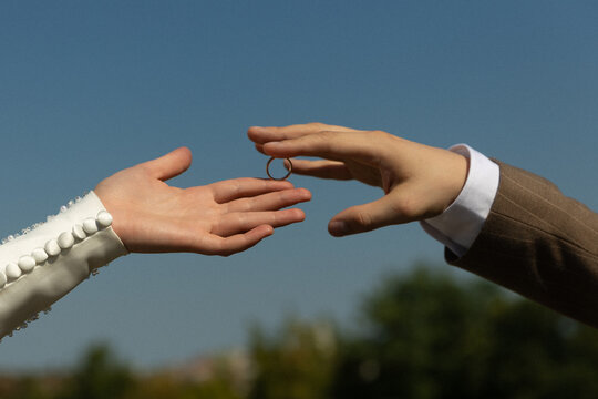 Wedding couple exchange ring between outstretched hands
