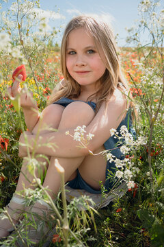 Young girl hold strawberry in blooming poppy field