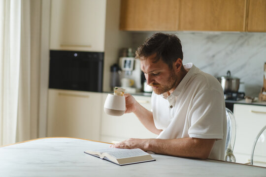 Man read Bible and drink tea at kitchen table
