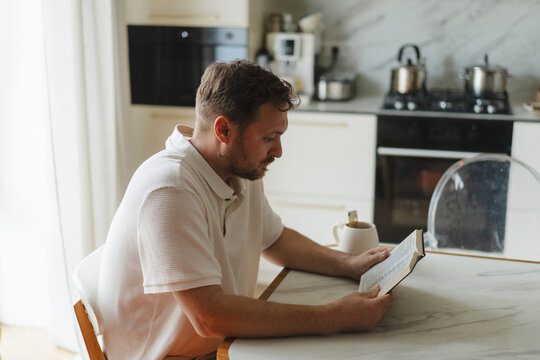 Man reading Bible at kitchen table during quiet morning
