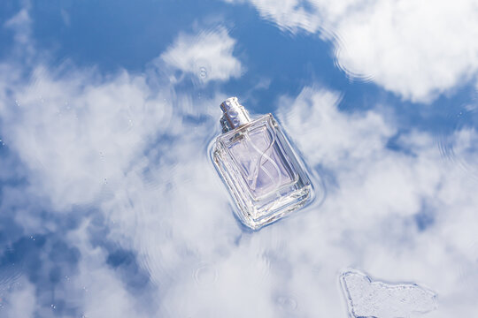 Perfume bottle floating on bright cloudy blue sky