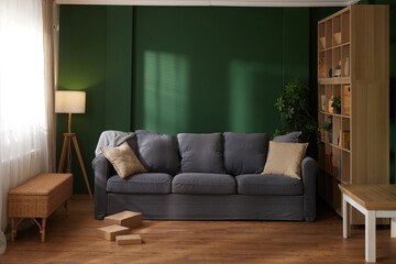Cozy living room interior with gray sofa, floor lamp, bookshelf and sunlight on wall. © Stockphotodirectors