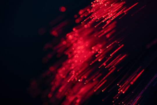 Red fiber optic light trails on dark technology background