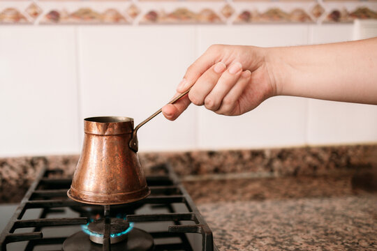 Hand heat copper coffee pot on gas stove