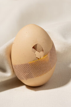 Cracked egg with bandage as fragile mental health allegory