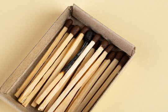 Burnt matchstick among wooden matchstick in open box