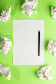 Blank paper and pencil amid crumpled paper on green