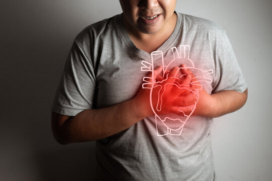 Man clutching his chest in pain with a digital glowing red human heart graphic overlay. Concept of heart attack, cardiovascular disease, chest pain, and emergency medical cardiology.
