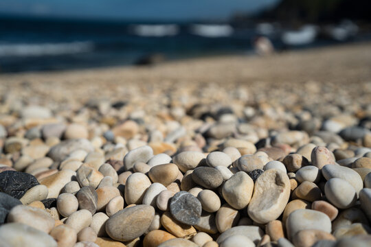 Smooth pebble texture on a sunlit beach shoreline