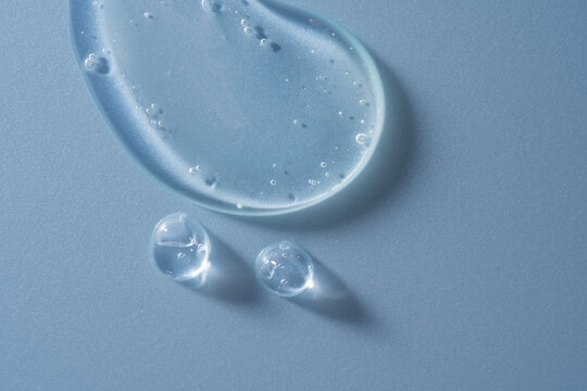 Transparent cosmetic gel smear with bubbles on blue background