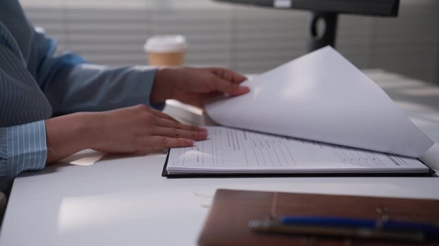 Office professional reviewing printed financial reports beside a computer keyboard and paperwork, representing accounting verification, bookkeeping review, financial analysis, and administrative organ