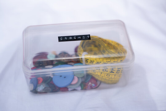 Crochet button and measuring tape in clear storage box