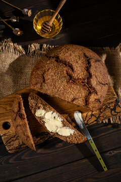 Rustic rye bread loaf with butter and honey on wood