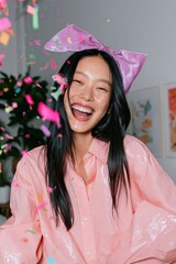 Fototapeta premium Joyful young woman laughing with confetti and a large pink bow for party poster and celebration background with playful vibes