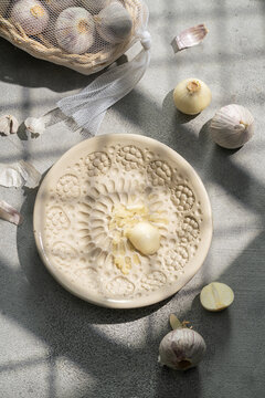 Garlic and ceramic plate grater in sunlight