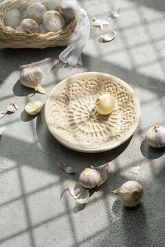 Garlic and ceramic plate grater in window sunlight