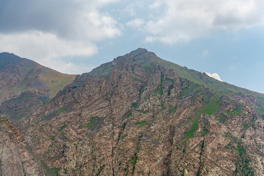 Rocky Shakhter peak with a steep northern slope under dark clouds before an approaching thunderstorm, Uzbekistan.