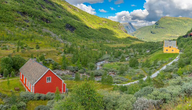 Red farmhouse in lush Norwegian fjord valley landscape