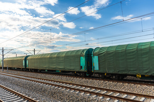 Freight train at railway station beside open field