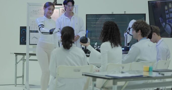 Engineers test the wearable robotic hand by gripping a ball in front of the seated team, the colour coded tactile pressure map updating on the laboratory screen.