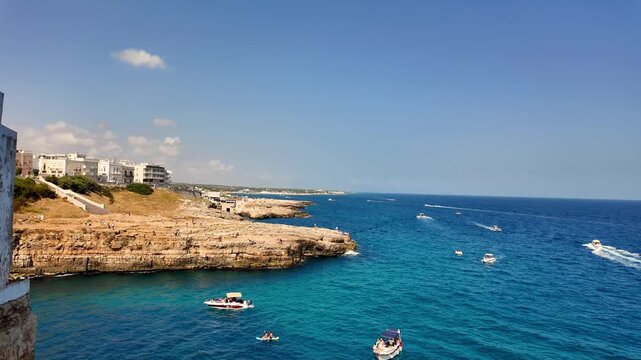 Stunning 4K footage of the famous Lama Monachile beach in Polignano a Mare, Puglia, Southern Italy. Crystal clear turquoise water, white limestone cliffs, and historic houses of the old town hanging o