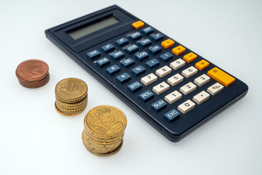 Calculator with euro coins arranged on a white surface for counting money