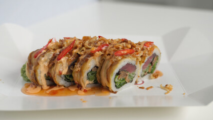 Gourmet tuna maki sushi rolls with spicy sauce and crispy onions in a takeaway container, ready for delivery © Volodymyr_sh