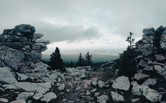 Rocky mountain path leading to a misty forest valley