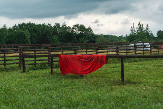 Red cloth hanging on a wooden fence in a green field