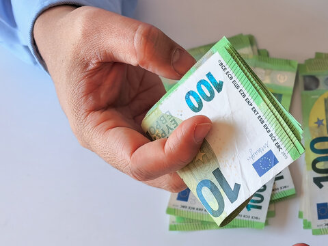 Man holding a stack of one hundred euro banknotes close up.