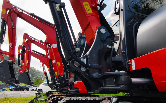 Compact hydraulic excavators parked outdoors with buckets lowered and metal tracks
