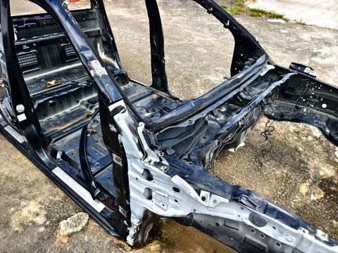 Charred metal car shell with exposed frame rails and burnt interior floor pans 