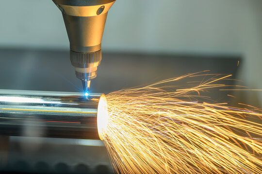 Laser beam from a fiber laser cutting machine engraving a steel pipe with sparkling light