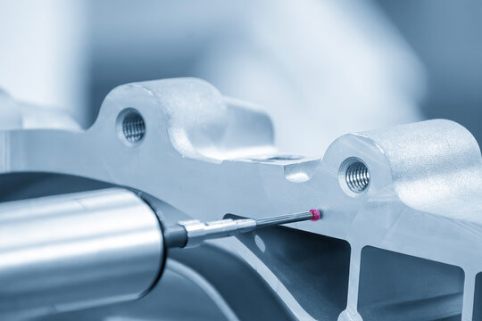 Multi-axis CMM machine measuring aluminum parts with a touch probe in a blue tone scene