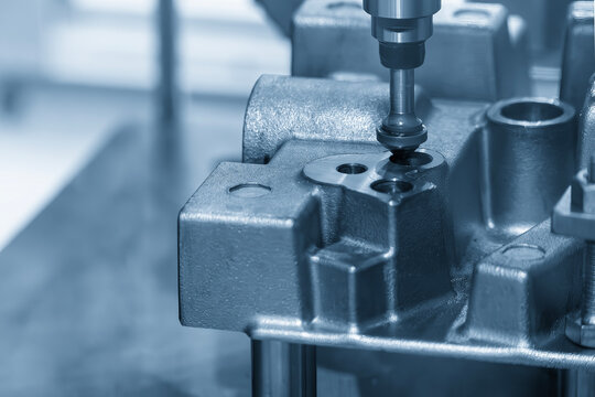 The hole deburring process on metal casting parts using a chamfer tool in a blue tone scene