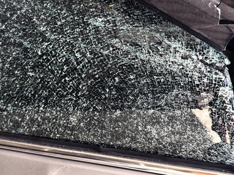 Damaged car windshield and hood with shattered glass and bent trim after impact