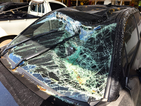 Silver car with heavy collision damage parked inside repair garage
