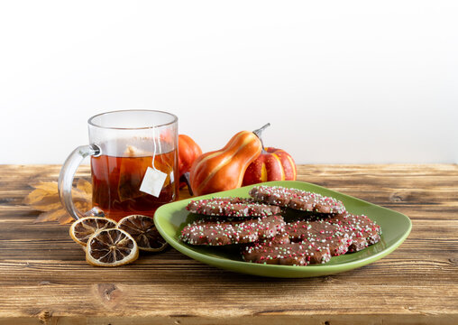 Cozy autumn still life with chocolate cookies, tea, dried citrus, and small decorative pumpkins   