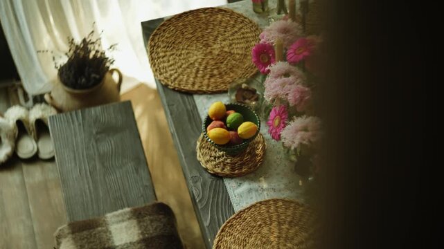 Wooden dining table decorated with fresh flowers and straw placemats during daylight
