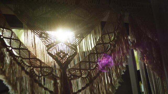 Macrame curtain hanging over window indoors during daytime with bright sunlight shining through
