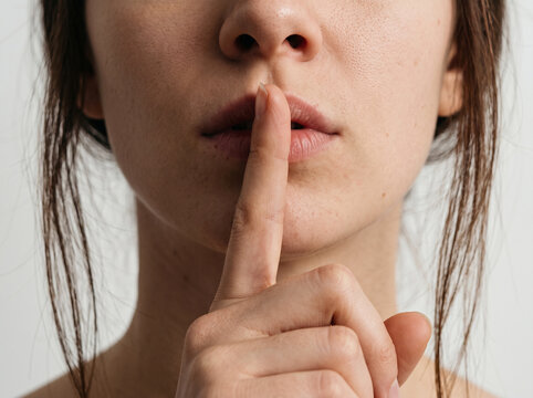Close-up of woman with index finger on lips making silence gesture
