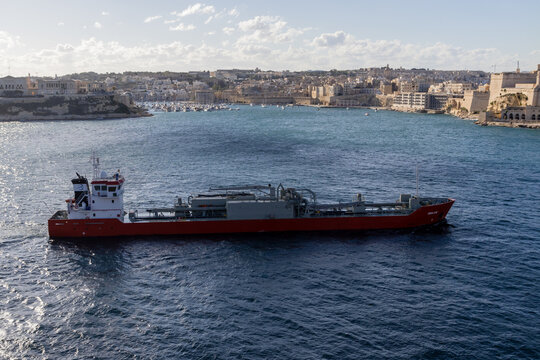 Valletta, Malta - October 14th, 2026 Red Chemical Tanker Ship Sailing Past Historic Mediterranean Harbor And City Waterfront