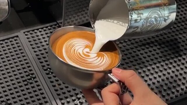 Barista holding a cup of freshly brewed coffee with intricate rosetta and tulip latte art pattern