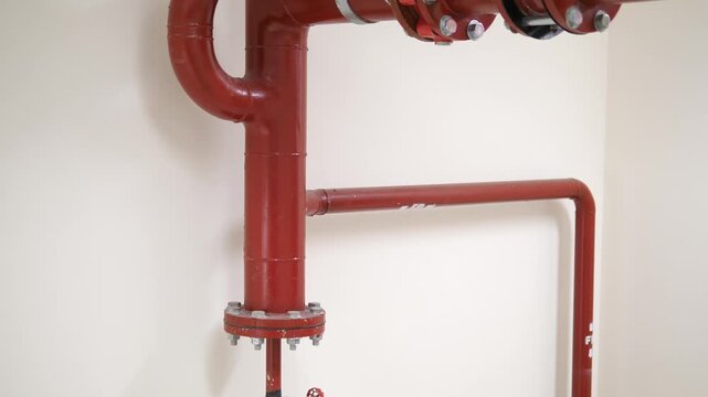 Close up of red fire sprinkler pipe system and flanged joints in building