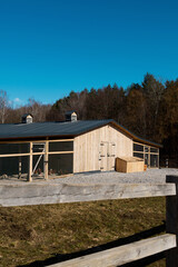 A modern wooden chicken coop with a large mesh pen on a farm on a sunny day against a blue sky. © Аліна Костюк