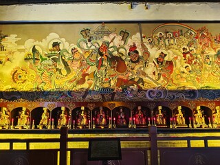 Colorful ancient Chinese temple mural with deities and golden statues © Duangtida