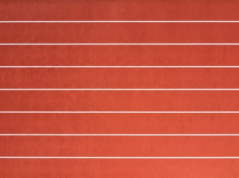 Red running track surface with white lane lines, textured rubber athletic stadium floor, sport competition ground background, fitness training and athletics track pattern