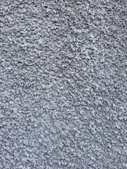 Close-up of a rough gray stucco wall with coarse granular plaster texture and an uneven cement surface. Detailed architectural background featuring a uniform light gray color, porous structure © mook