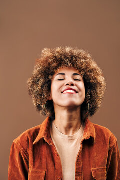 Joyful woman with curly hair smiling in warm studio portrait